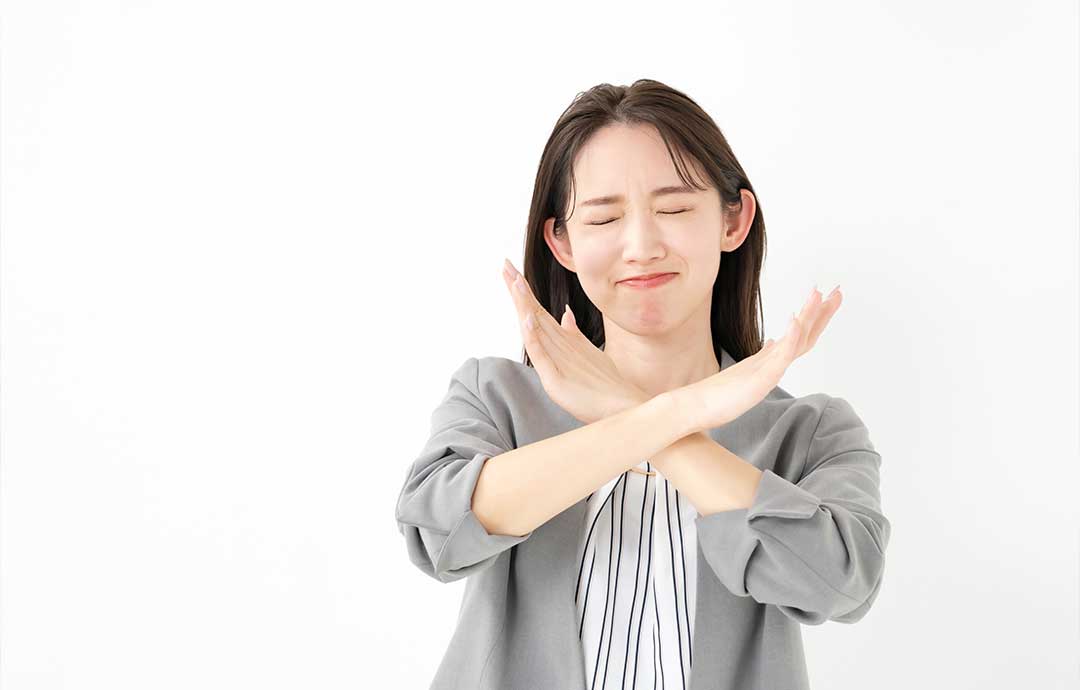 手でバツを作る女性