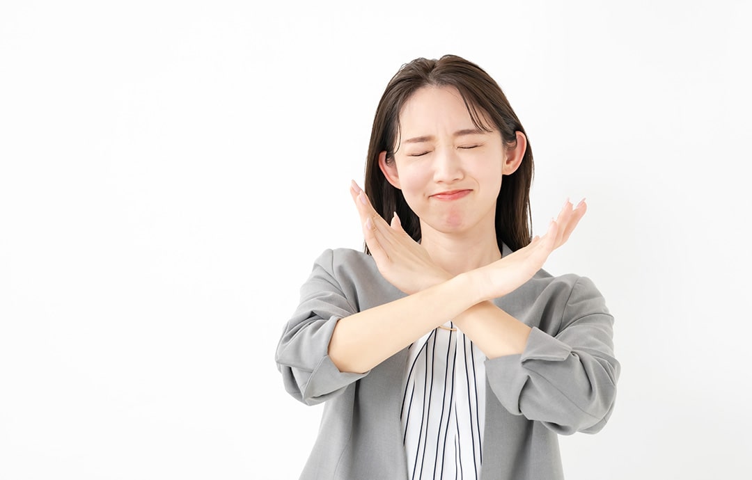 手でバツを作る女性