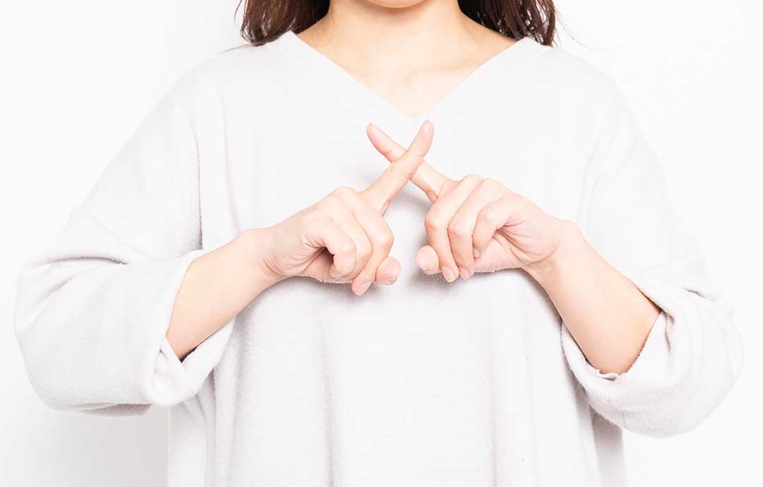 指でバツを作る女性