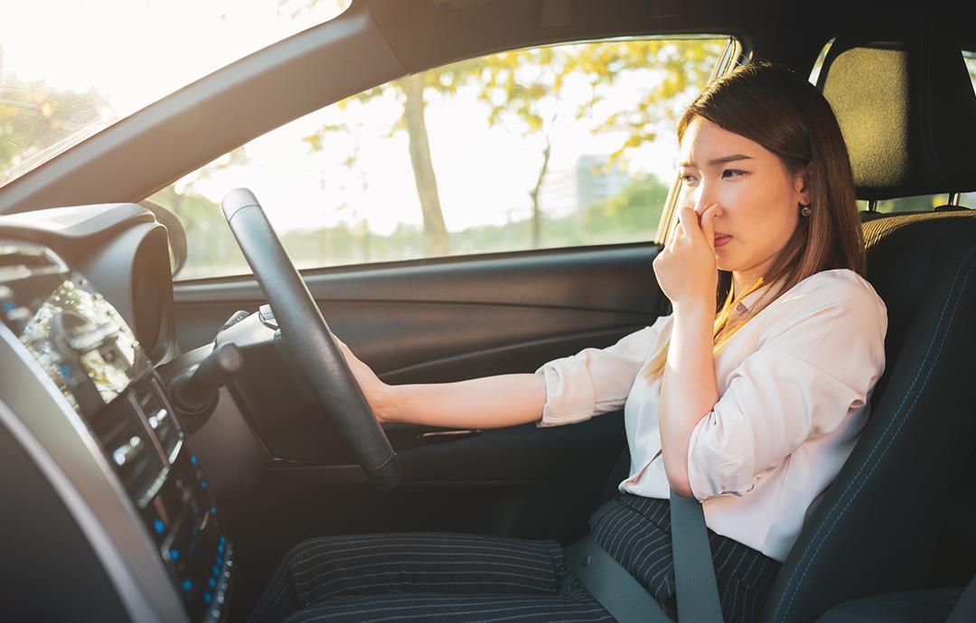 運転席で鼻をつまむ女性